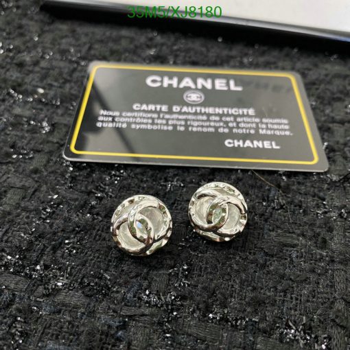 Chanel earrings with authenticity card on black texture.