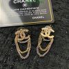 Chanel logo earrings with chains on a dark background.