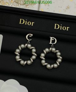 Pearl hoop Dior earrings on black display.