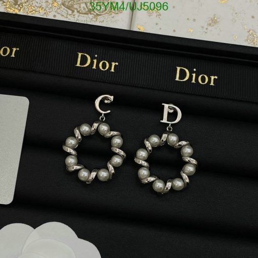 Pearl hoop Dior earrings on black display.