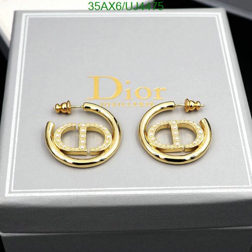 Gold designer logo earrings with crystals on display box.