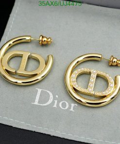 Gold designer logo earrings with pearls on gray background.