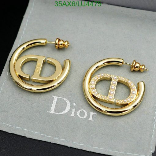 Gold designer logo earrings with pearls on gray background.