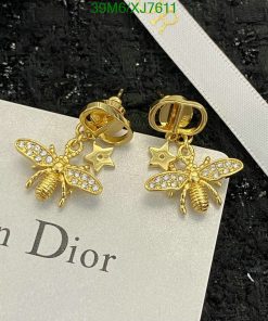 Gold bee and star earrings on textured background.