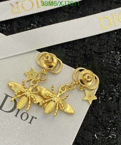 Gold bee and star dangle earrings on branded card.