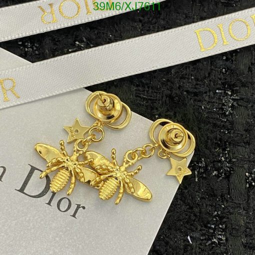 Gold bee and star dangle earrings on branded card.