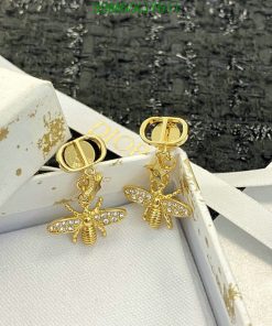 Gold bee-shaped earrings with diamonds on white box.