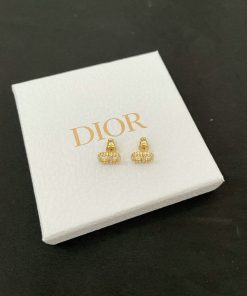 Gold Dior earrings on white display box.