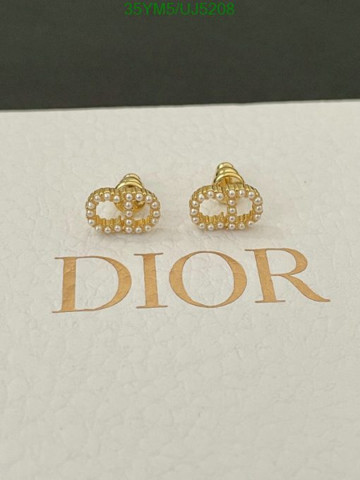 Gold Dior pearl-studded earrings on white surface