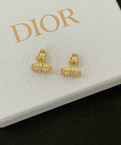 Gold designer logo earrings on branded display box.