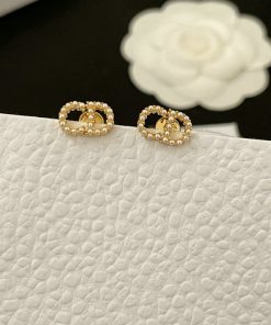 Gold beaded hoop earrings on white texture.