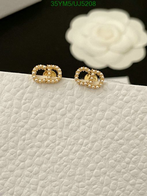 Gold beaded hoop earrings on white texture.