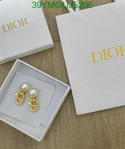 Dior jewelry box with pearl earrings on wood surface.