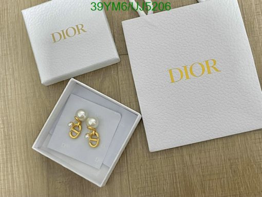 Dior jewelry box with pearl earrings on wood surface.