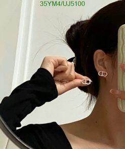 Woman trying on silver hoop earrings, mirror reflection.