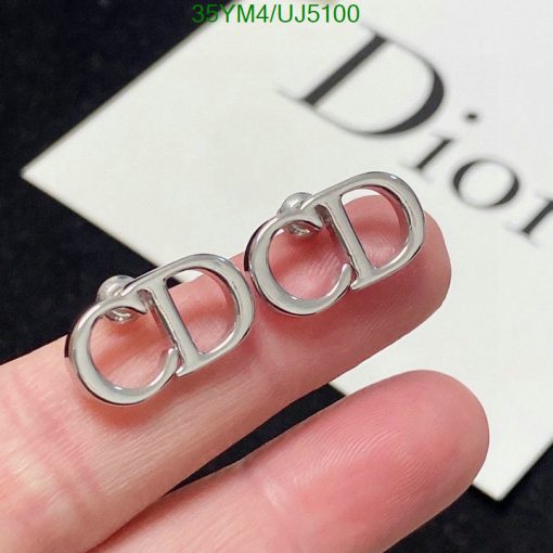 Silver designer logo earrings on finger.