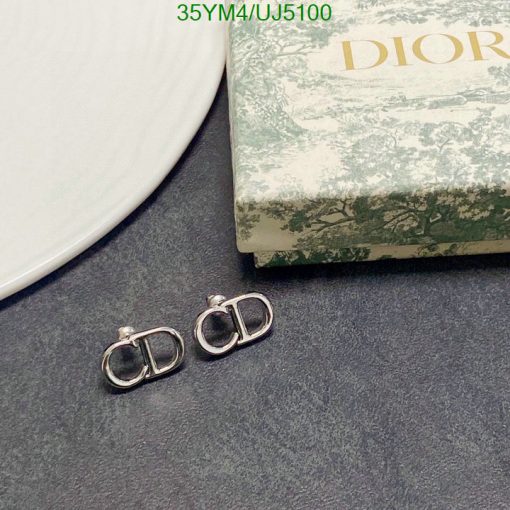 Dior logo earrings on textured surface with box.