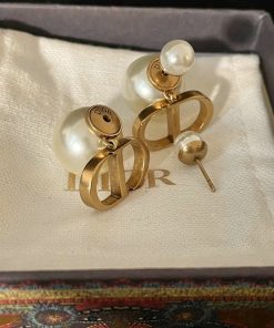 Pearl earrings with gold designer logo in box.