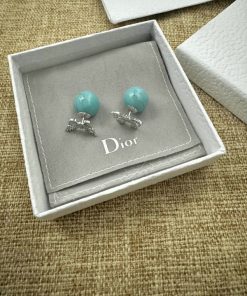 Turquoise earrings in branded box on textured surface.