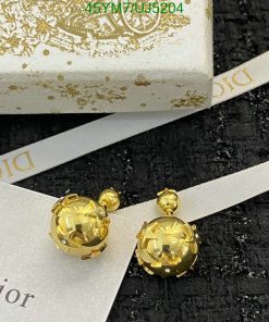 Gold Dior earrings with packaging on black texture.