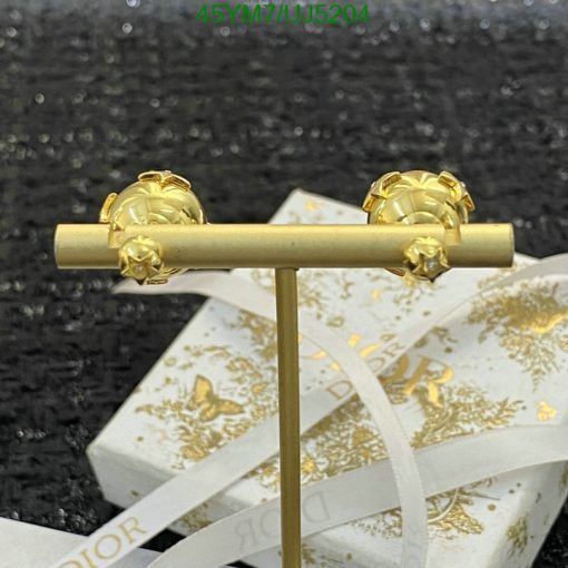 Gold designer earrings on display stand with ribbon.