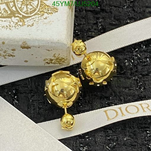 Gold designer dangling earrings on branded packaging.