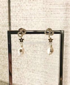 Pearl drop earrings with star accents on display.