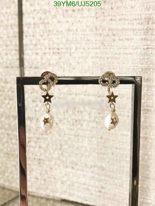 Pearl drop earrings with star accents on display.