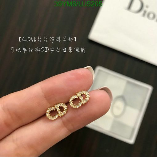 Gold earrings shaped like letters on a hand.