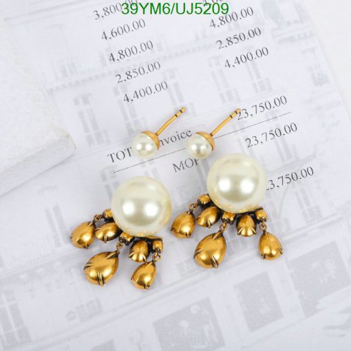 Pearl and gold floral dangle earrings on invoice background.