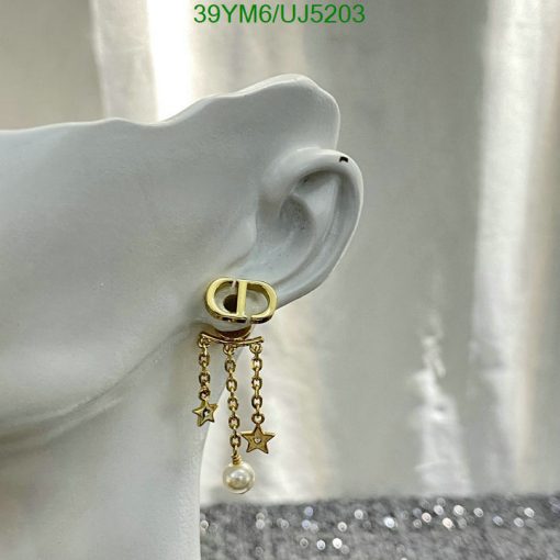 Gold hoop earring with star charms on mannequin ear.