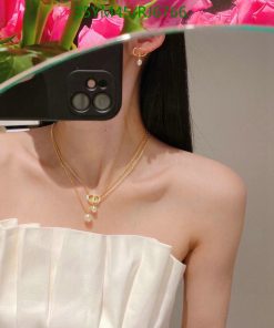 Woman taking selfie with flowers, gold jewelry visible.