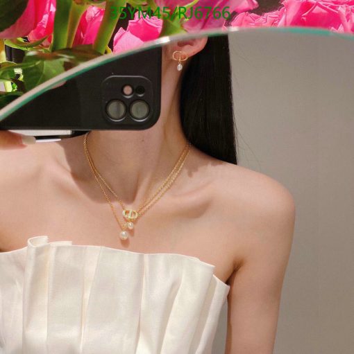 Woman taking selfie with flowers, gold jewelry visible.