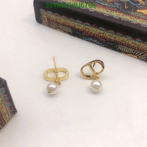 Gold pearl earrings on white surface.