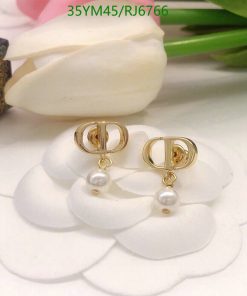 Gold pearl earrings on white petals.