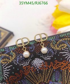 Pearl earrings on patterned textile background.