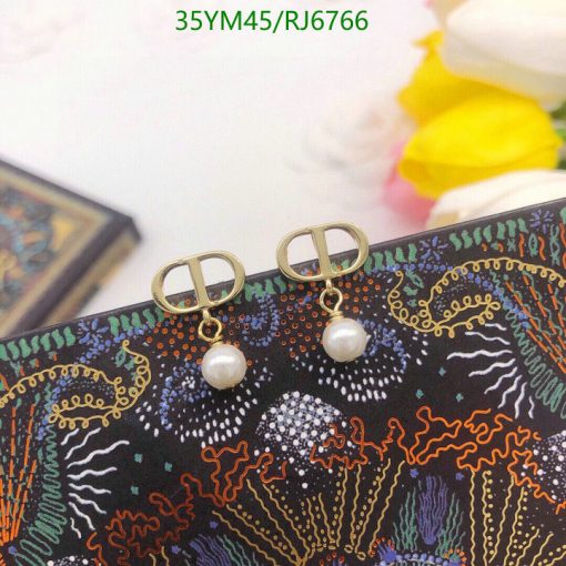 Pearl earrings on patterned textile background.