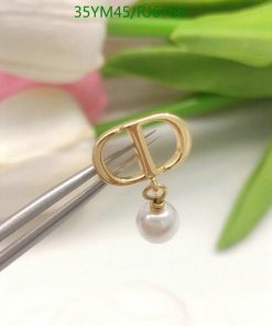 Gold earring with pearl detail, green leaves background.