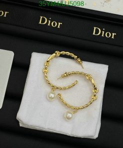 Gold pearl earrings on Dior branded display.