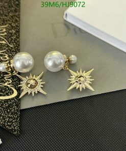 Gold sunburst earrings with pearls on desk.