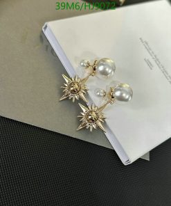 Gold starburst pearl earrings on book