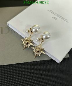 Pearl and starburst design golden earrings on white surface.