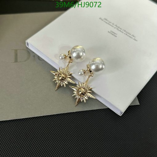 Pearl and starburst design golden earrings on white surface.