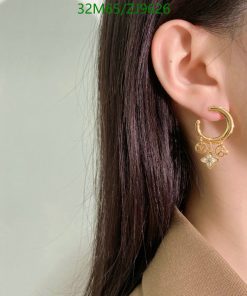 Woman wearing gold hoop earring with charms.