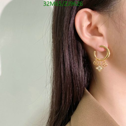 Woman wearing gold hoop earring with charms.