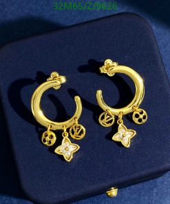 Gold charm hoop earrings on dark background.