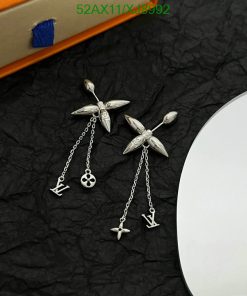 Silver insect-inspired earrings with logo charms on black surface.