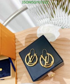 Designer logo earrings in box on wood surface