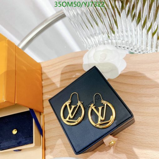 Designer logo earrings in box on wood surface