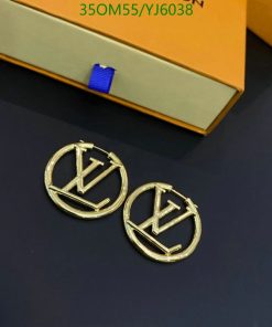 Designer logo earrings on dark surface near box.